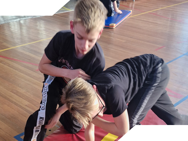 Tiener leden van Spartan Krav Maga worstelen met elkaar op de grond.